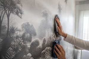 Iemand reinigt fotobehang voorzichtig met een microvezeldoek in een woonkamer